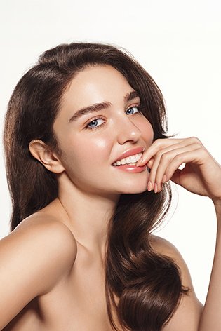 Uśmiechnięta kobieta o promiennej pełnej blasku cerze glass skin