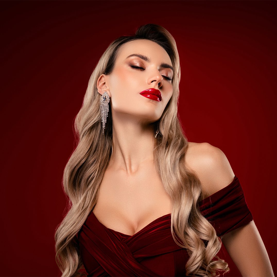 Piękna kobieta z długimi blond włosami i w bordowej sukience oraz wieczorowym makijażu