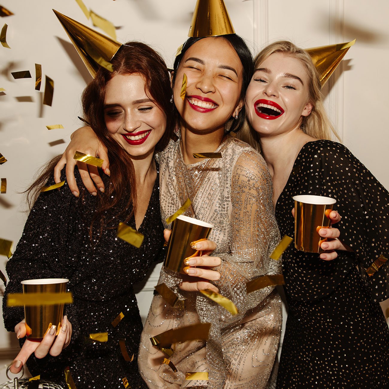 Przyjaciółki w makijażu na imprezę bawią się i trzymają złote kubki