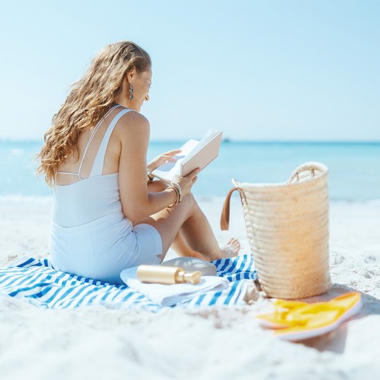 Kobieta czytająca książkę na plaży