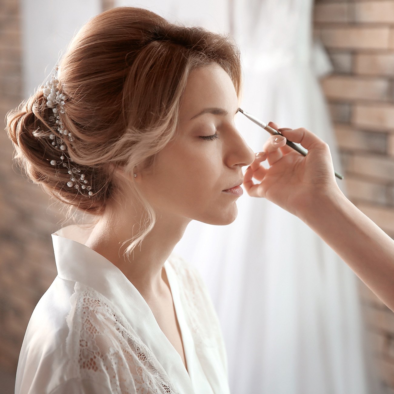 Makijażystka wykonuje subtelny makijaż pannie młodej