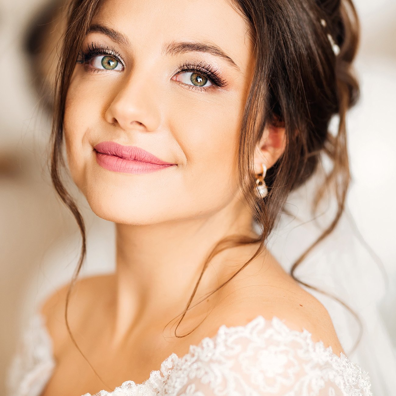 Brunetka w ślubnej stylizacji z makijażem w odcieniach nude.