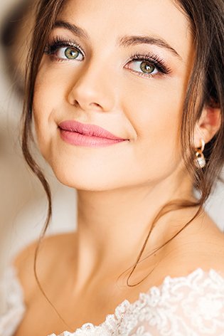 Brunetka w ślubnej stylizacji z makijażem w odcieniach nude.