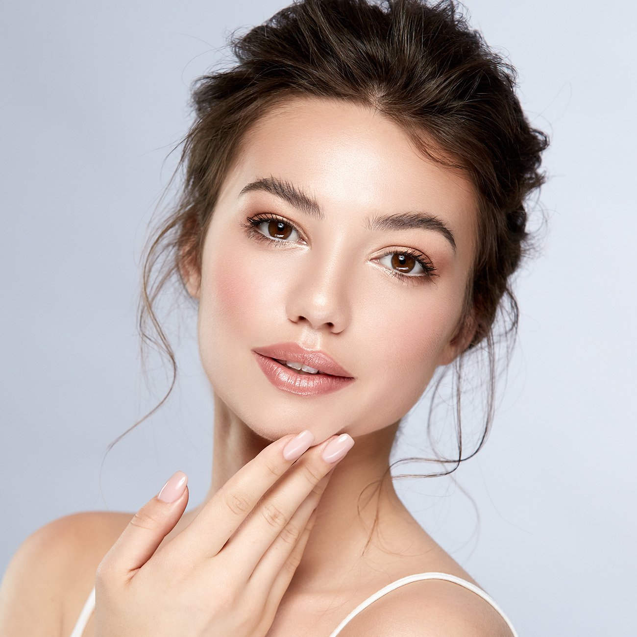 Młoda kobieta prezentuje naturalny makijaż o satynowo matowym wykończeniu i usta pokryte balsamem
