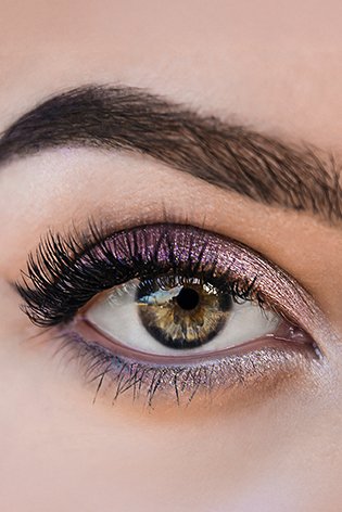 Zbliżenie na kobiece zielone oczy w fioletowym makeupie