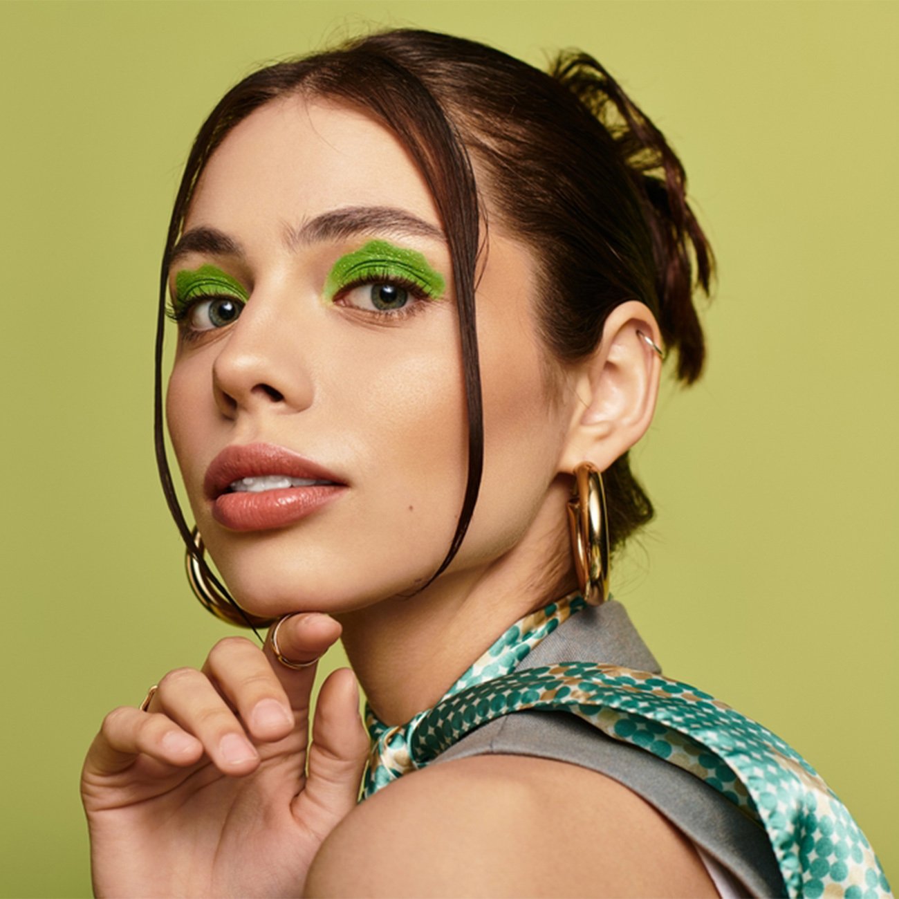 Młoda kobieta w zielonym makijażu oka na zielonym tle.