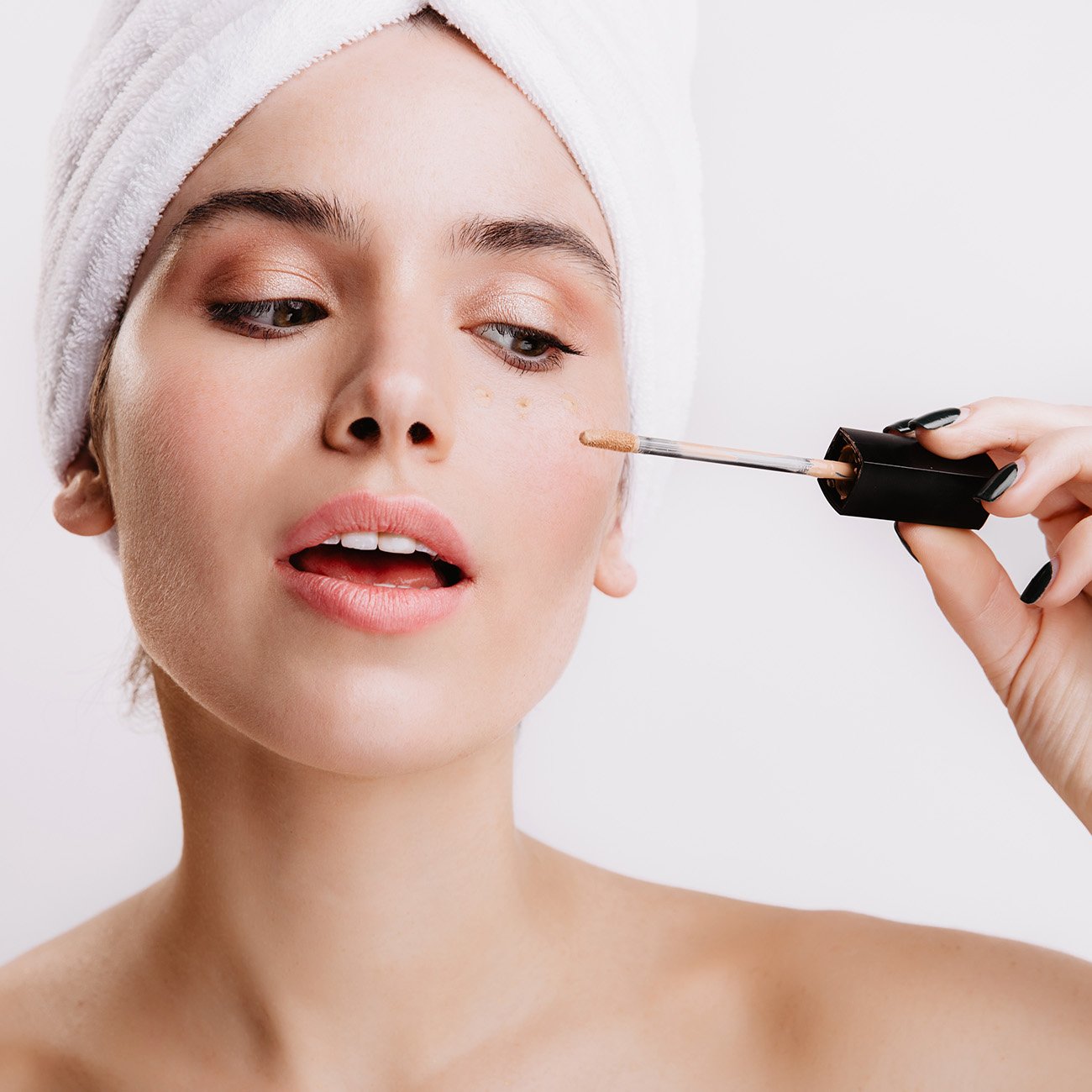 Młoda kobieta aplikuje pod oczy kremowy korektor