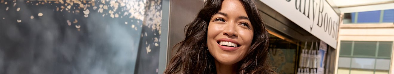 Uśmiechnięta kobieta na tle miasta, która ma nałożony krem BB Fit Me