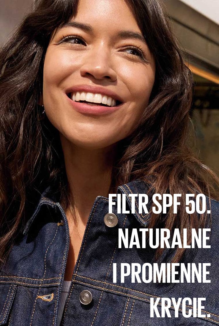 Kobieta w dżinsowej kurtce z szerokim uśmiechem. Komunikat Filtr SPF 50. Naturalne i promienne krycie.