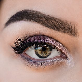Zbliżenie na kobiece zielone oczy w fioletowym makeupie